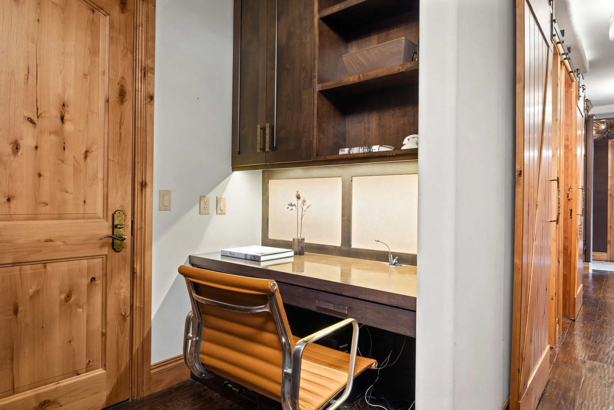 Integrated desk area featuring a light-colored desktop and dark wood-finish cabinetry with open shelving