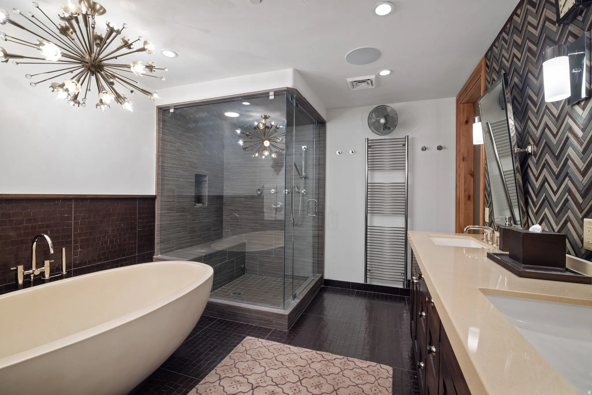 Freestanding soaking tub with floor-mounted faucet, oversized glass-enclosed shower with bench seating, and dual vanity with integrated sinks