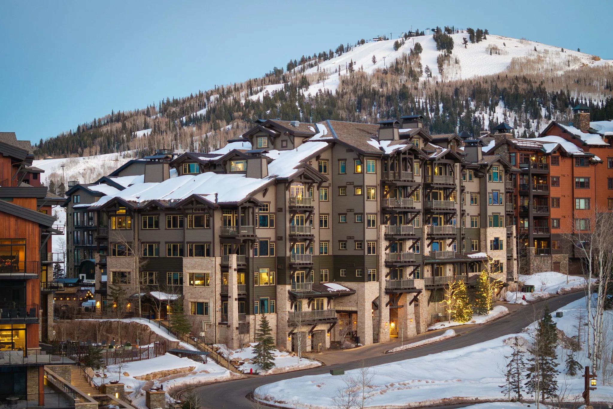 Multi-story building featuring stone and wood siding, multiple balconies, and a mountain backdrop