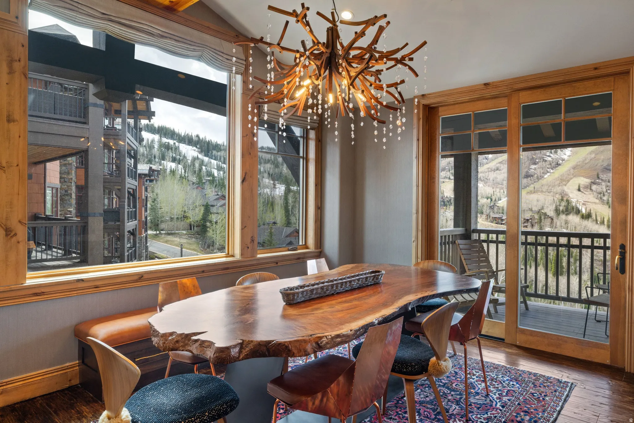 Dining area featuring a live-edge wood table, a unique branch-style chandelier with crystal accents, and wood-finish flooring