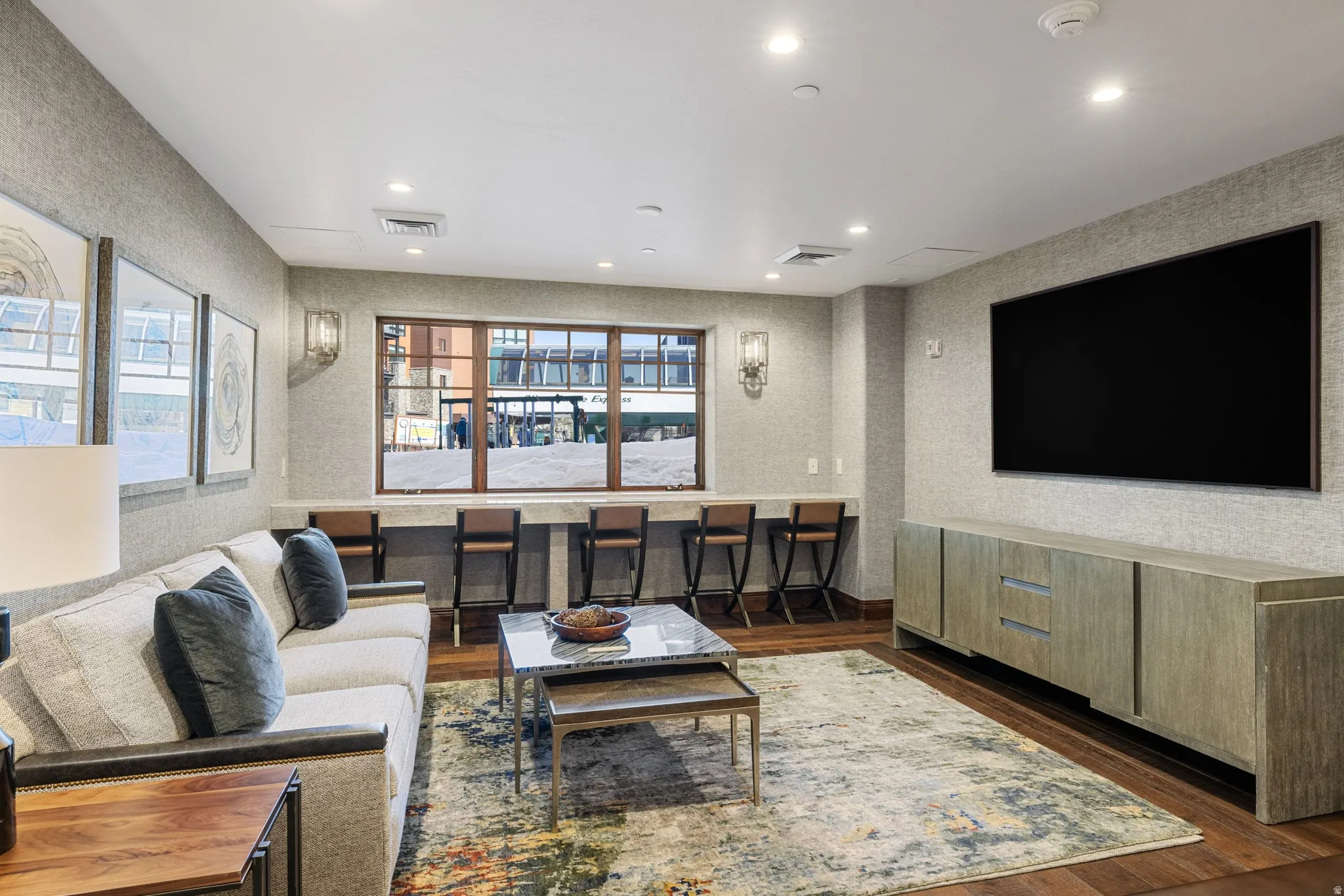 Spacious lounge area featuring rich wood-finish flooring and textured wall coverings