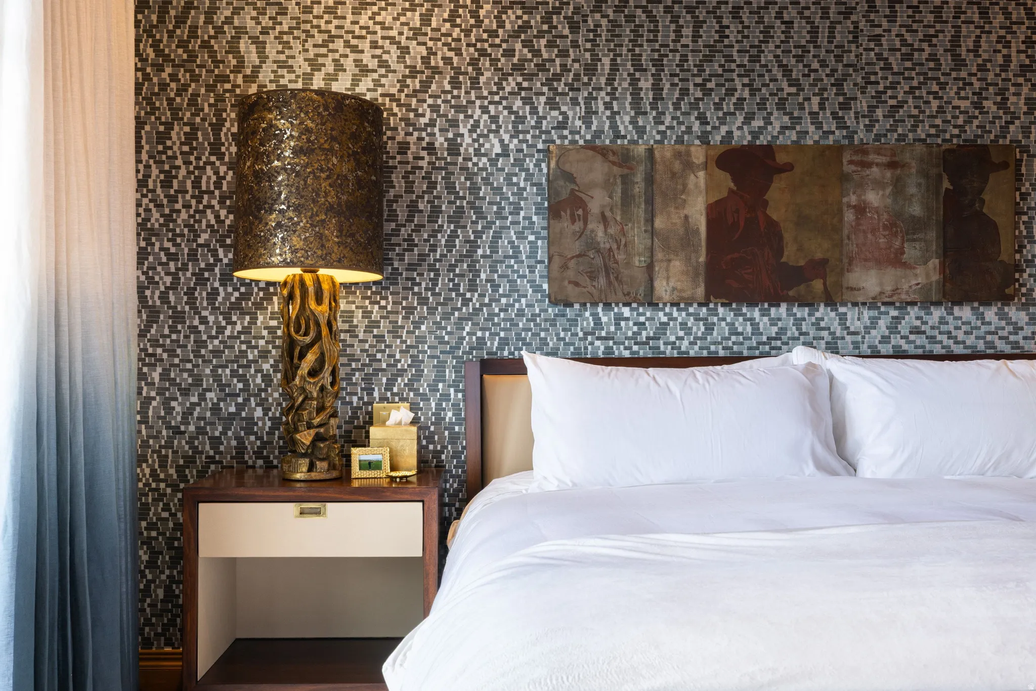 Feature wall with mosaic tile, a dark wood-finish nightstand with a single drawer, and light-filtering ombre drapes