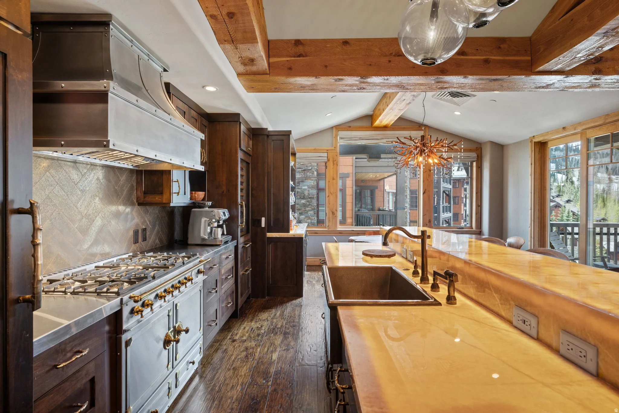 Gourmet kitchen featuring a professional-grade range with a custom metal hood, rich wood cabinetry, and a full backsplash