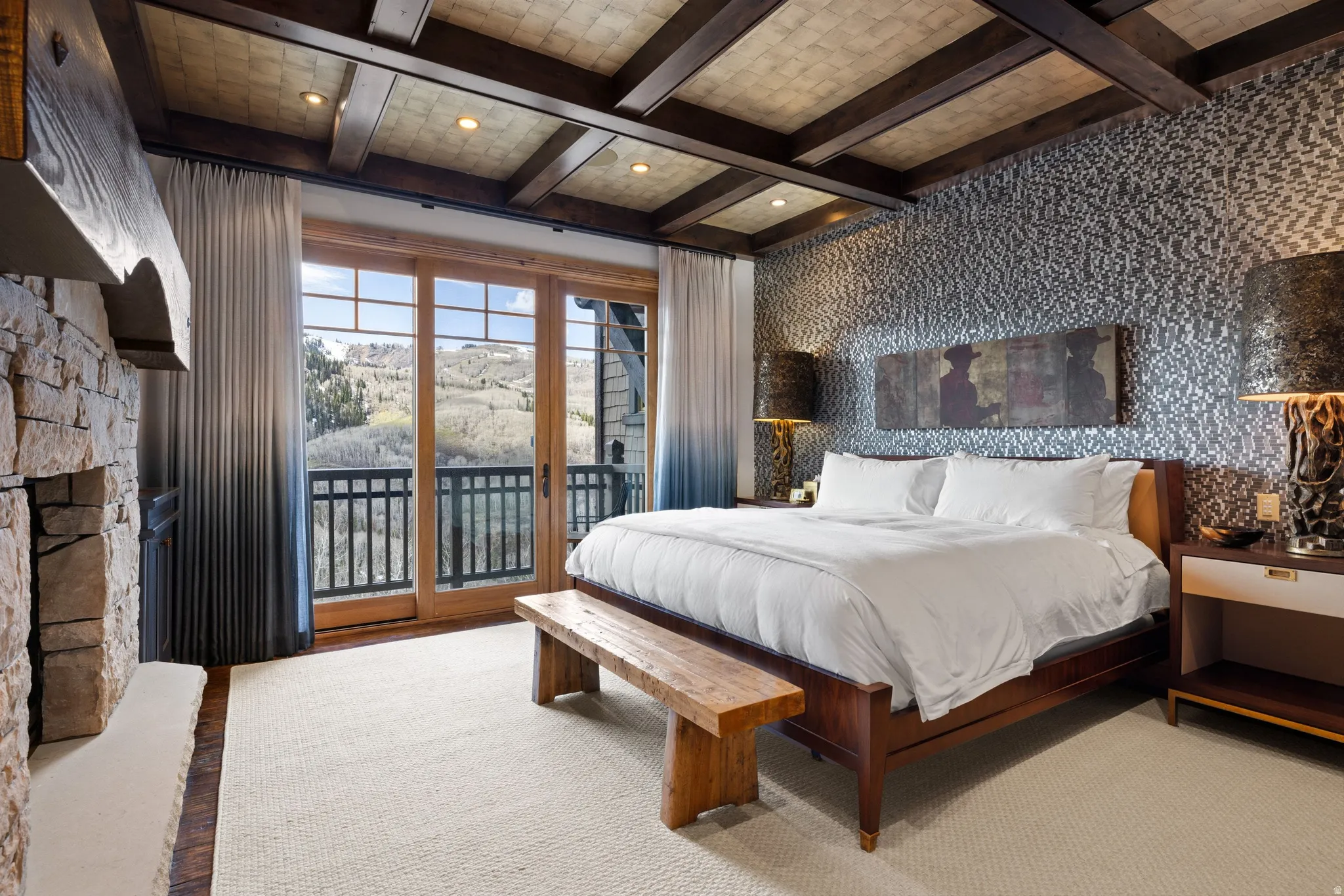 Stone fireplace with wood mantel, wood-beam ceiling with recessed lighting, wall-to-wall carpeting, and wood-framed sliding glass doors opening to a balcony