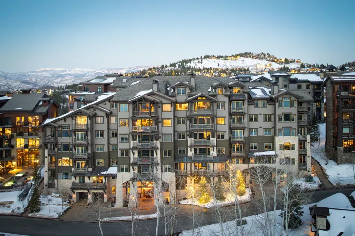 Multi-story condominium building featuring stone and wood-paneled exterior