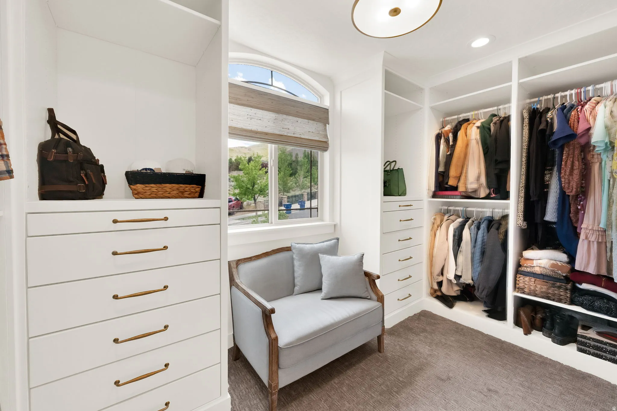 Custom closet system featuring built-in white cabinetry, multiple hanging rods, and integrated drawers with brass hardware