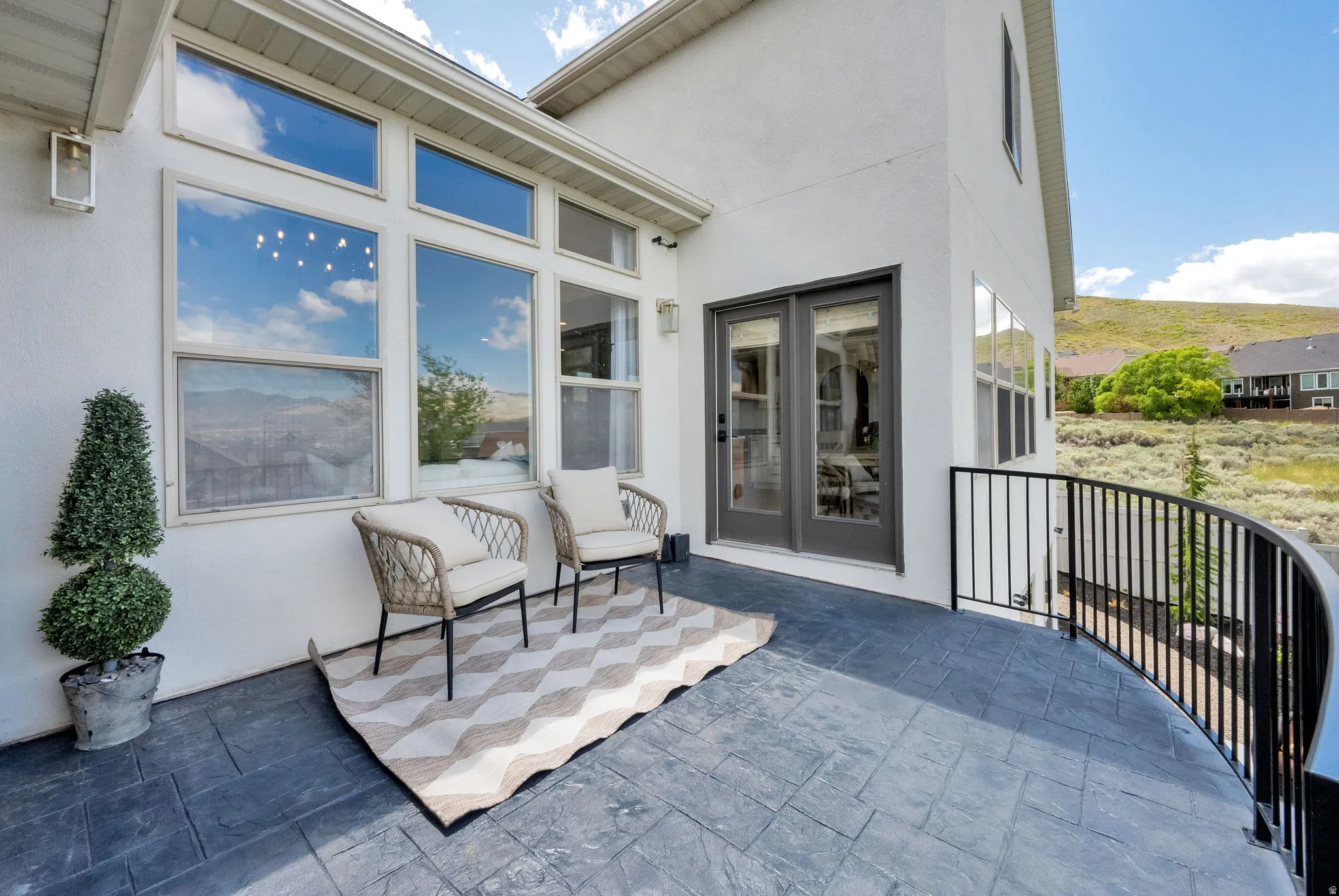 Curved patio with stamped concrete flooring and black wrought iron railing