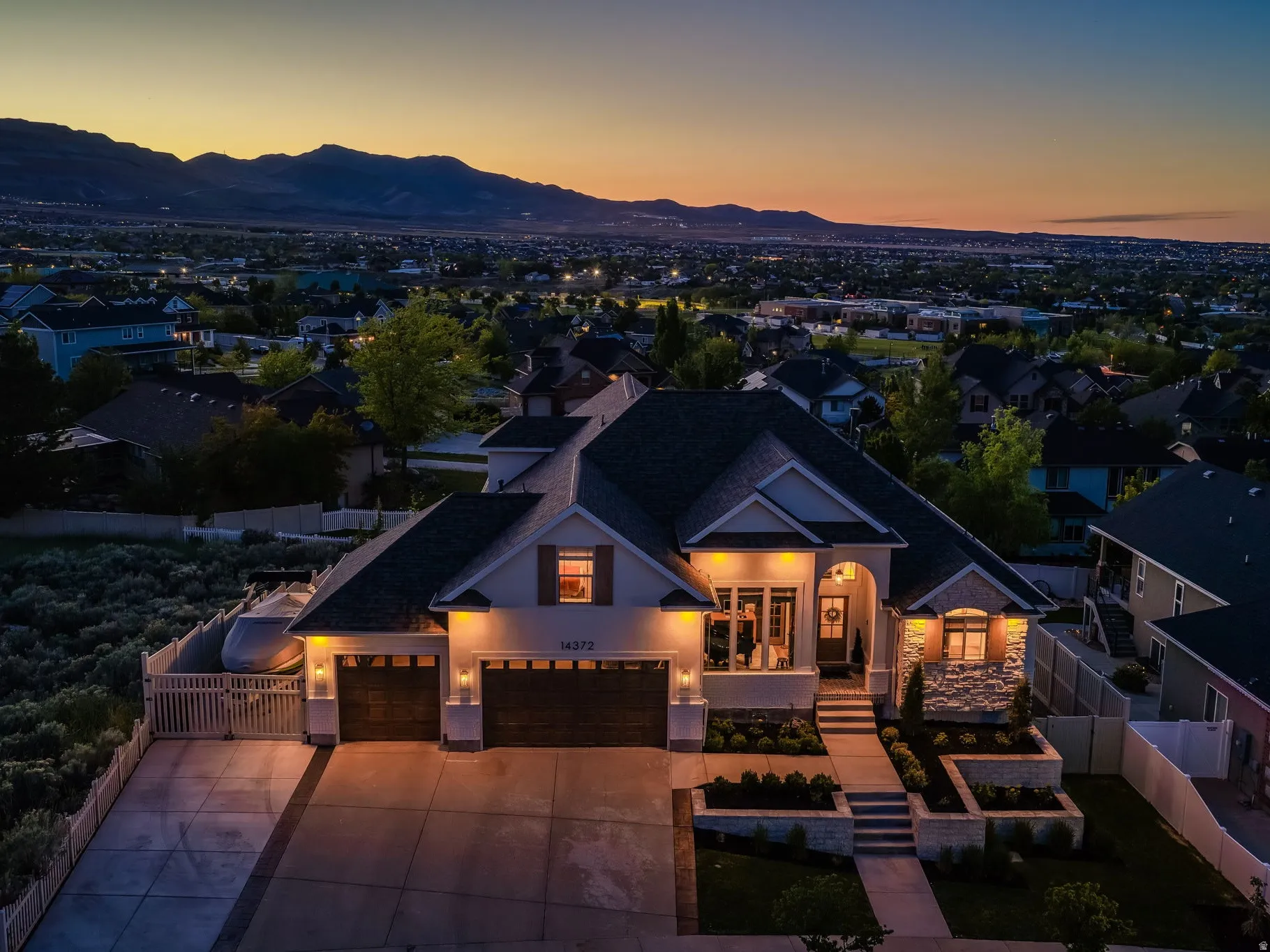 Modern residential exterior featuring stone accents, a multi-car garage, and tiered landscaping