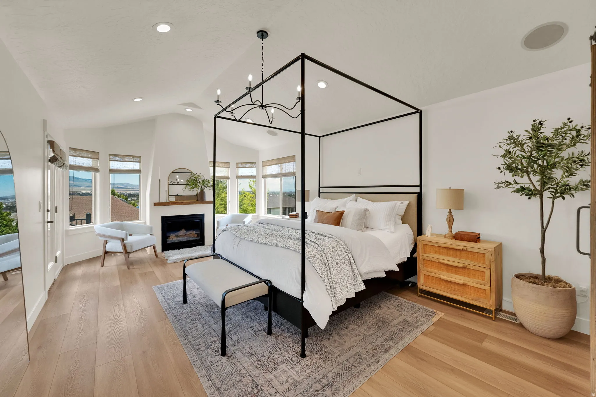Spacious room featuring vaulted ceilings, light wood-finish flooring, a built-in fireplace with wood mantel, multiple windows, and recessed lighting