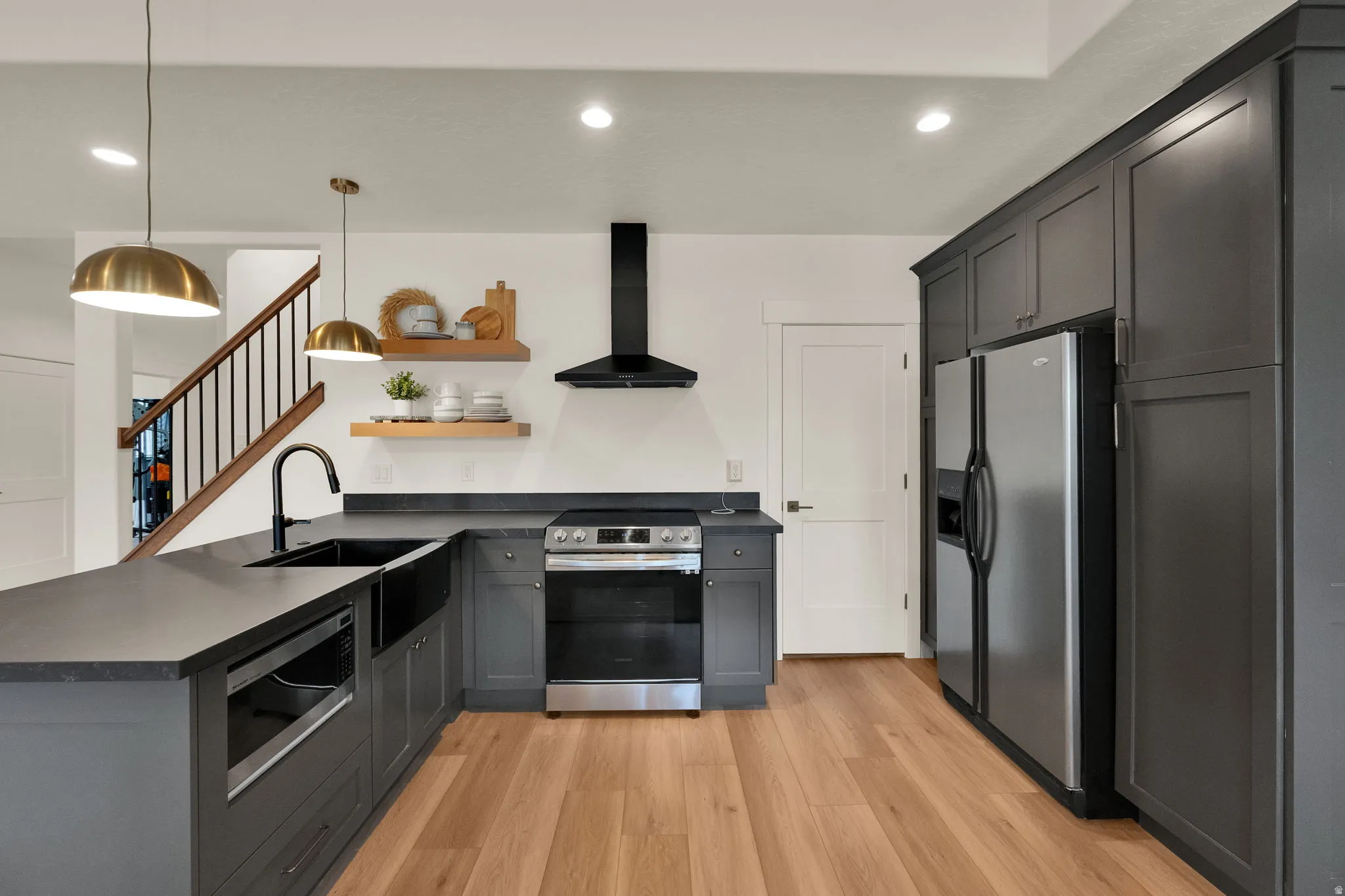 Kitchen featuring dark gray cabinetry, stainless steel appliances, dark countertops, and wood-finish flooring