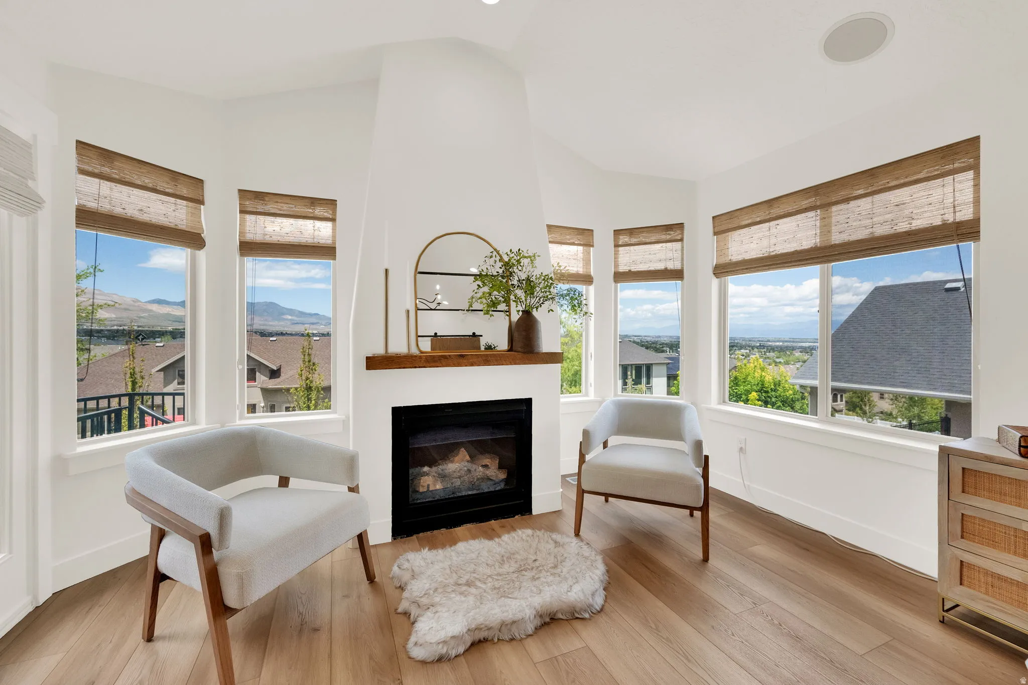 Spacious corner with multiple windows, a built-in fireplace, natural wood-finish flooring, and a recessed ceiling light fixture