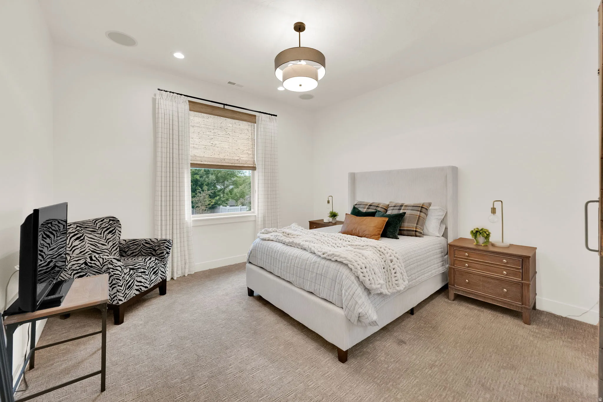Carpeted bedroom featuring a window with woven shades and drapes, recessed lighting, and a drum pendant light fixture