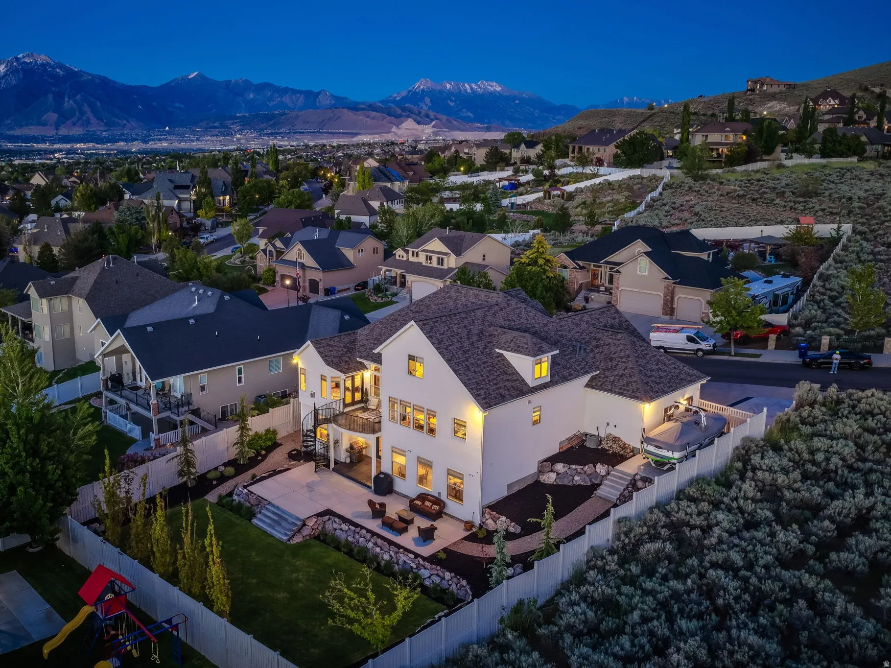 Expansive property featuring a multi-level stone patio, mature landscaping, and a manicured lawn