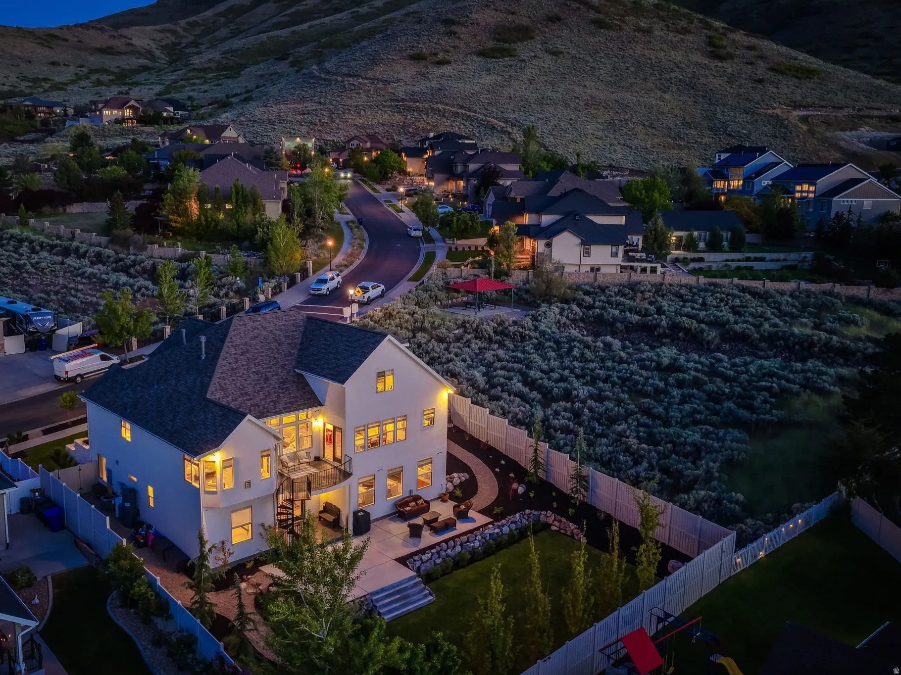 Two-story residence featuring a tiered rear patio, white privacy fencing, and a landscaped backyard with a lawn area
