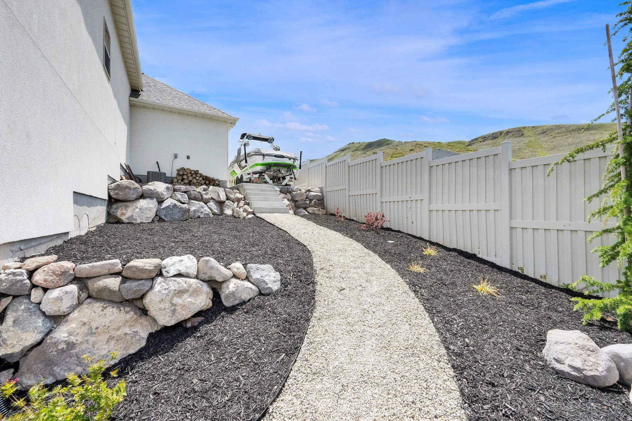 Gravel pathway bordered by dark mulch and natural rock landscaping