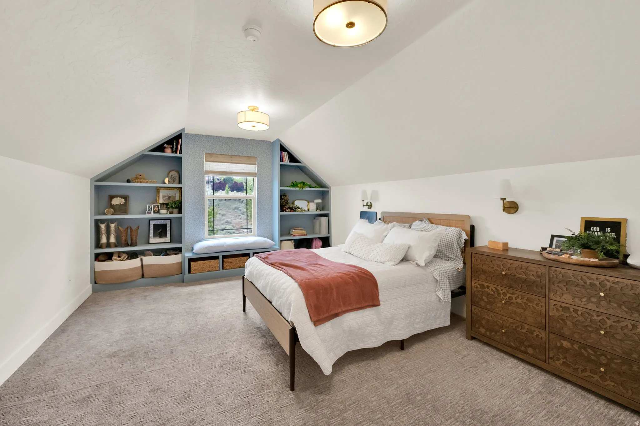 Attic bedroom featuring pitched ceilings, built-in shelving with a window seat, wall sconces, and a flush-mount ceiling light