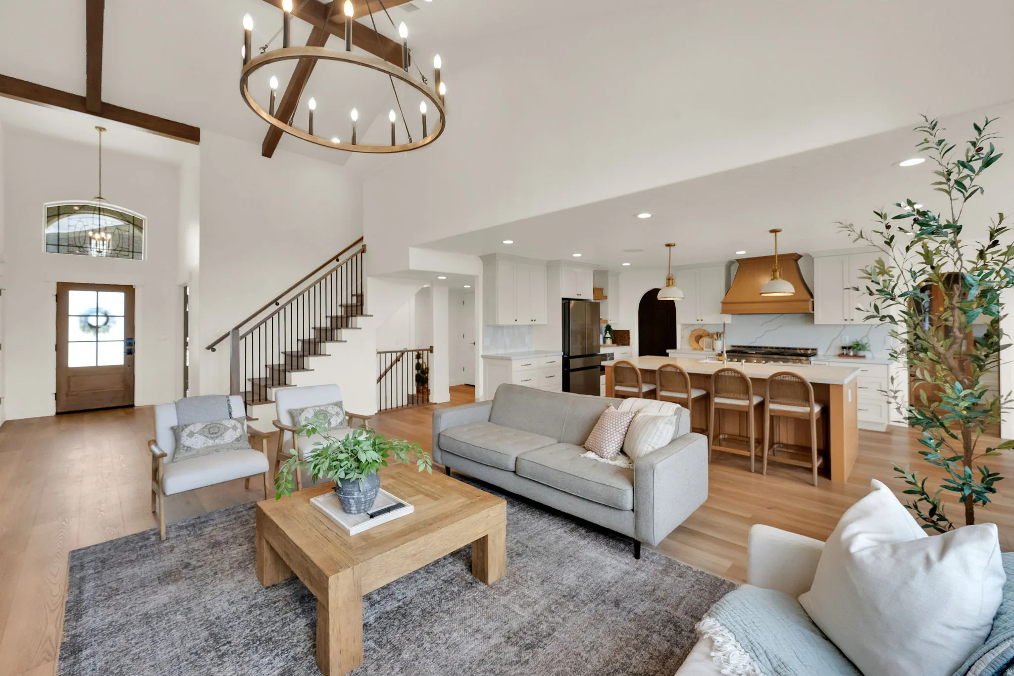 Open-concept living space featuring wood-finish flooring, a two-story entryway, and a prominent staircase with metal balusters