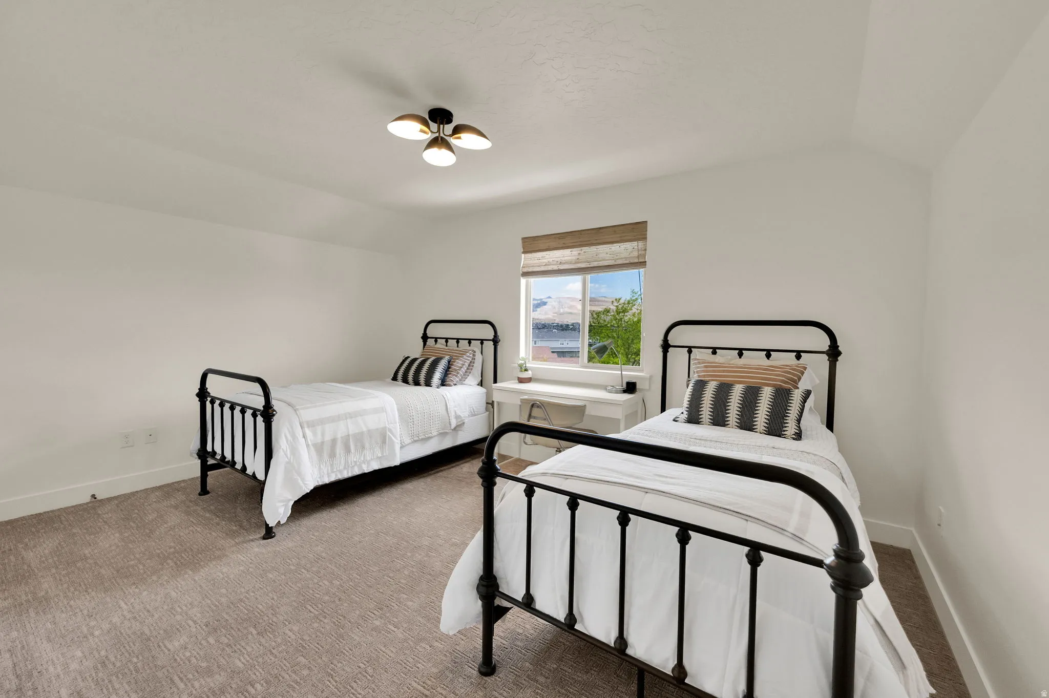 Carpeted room with a pitched ceiling and a window featuring a roller blind