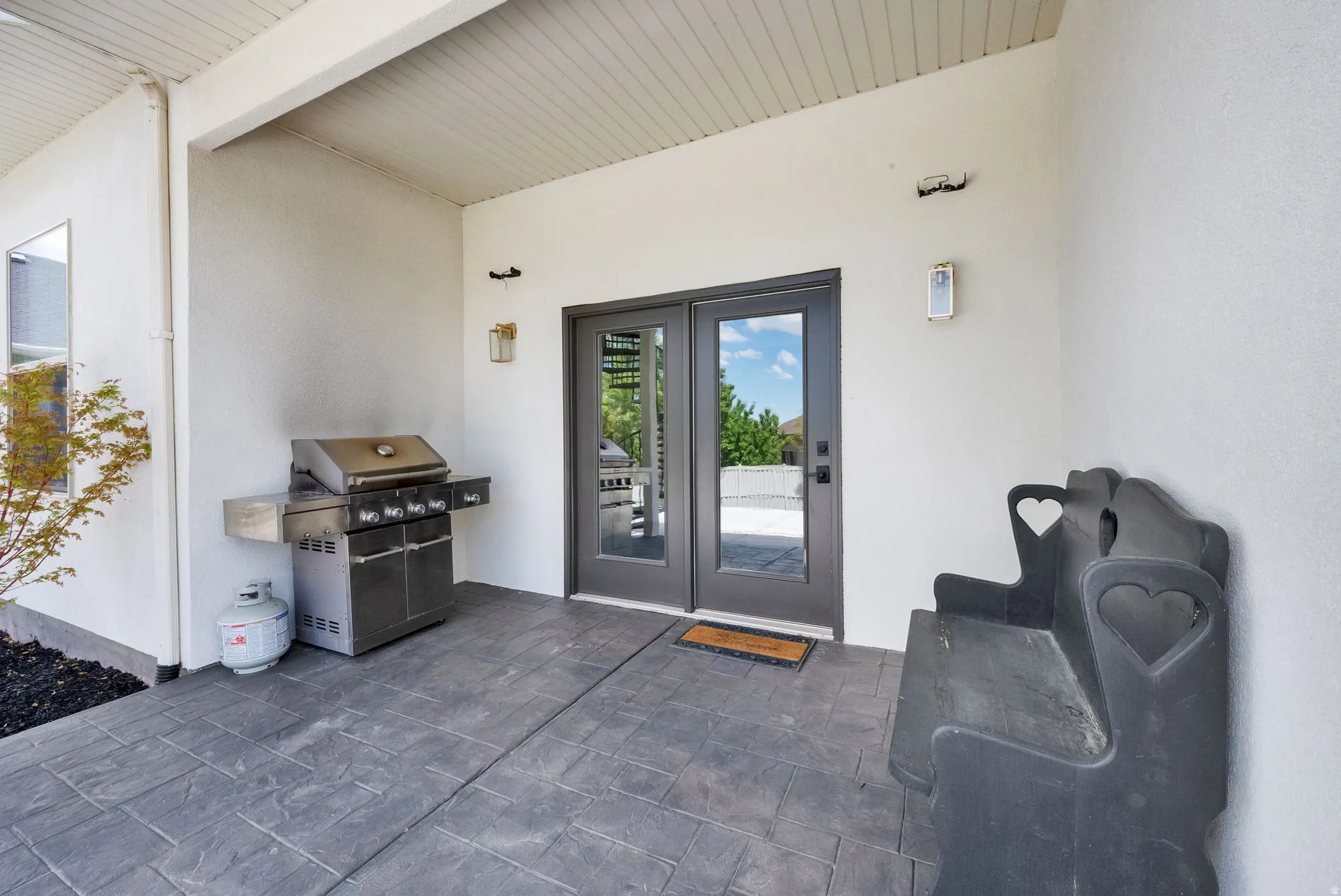 Covered outdoor patio featuring stamped concrete flooring, white stucco walls, and a recessed ceiling
