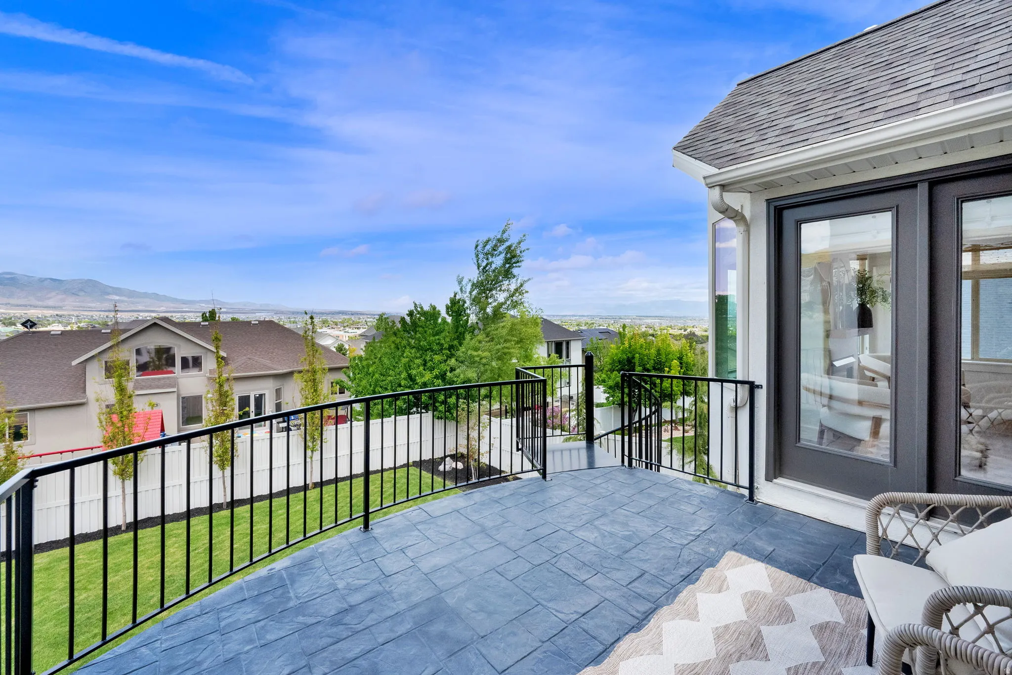 Expansive stamped concrete patio with black metal railings, offering an elevated perspective of the surrounding landscape
