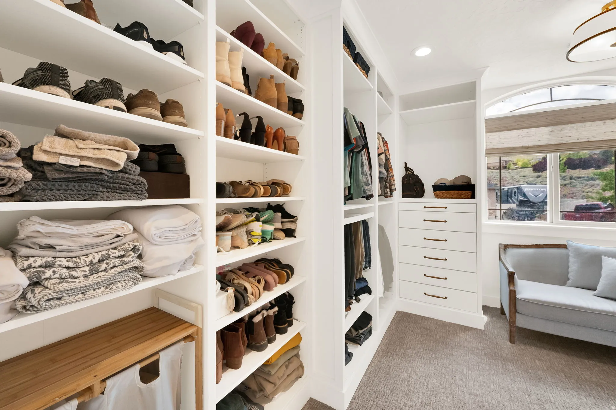 Spacious walk-in closet featuring extensive built-in shelving, integrated drawers with dark hardware, and ample hanging space
