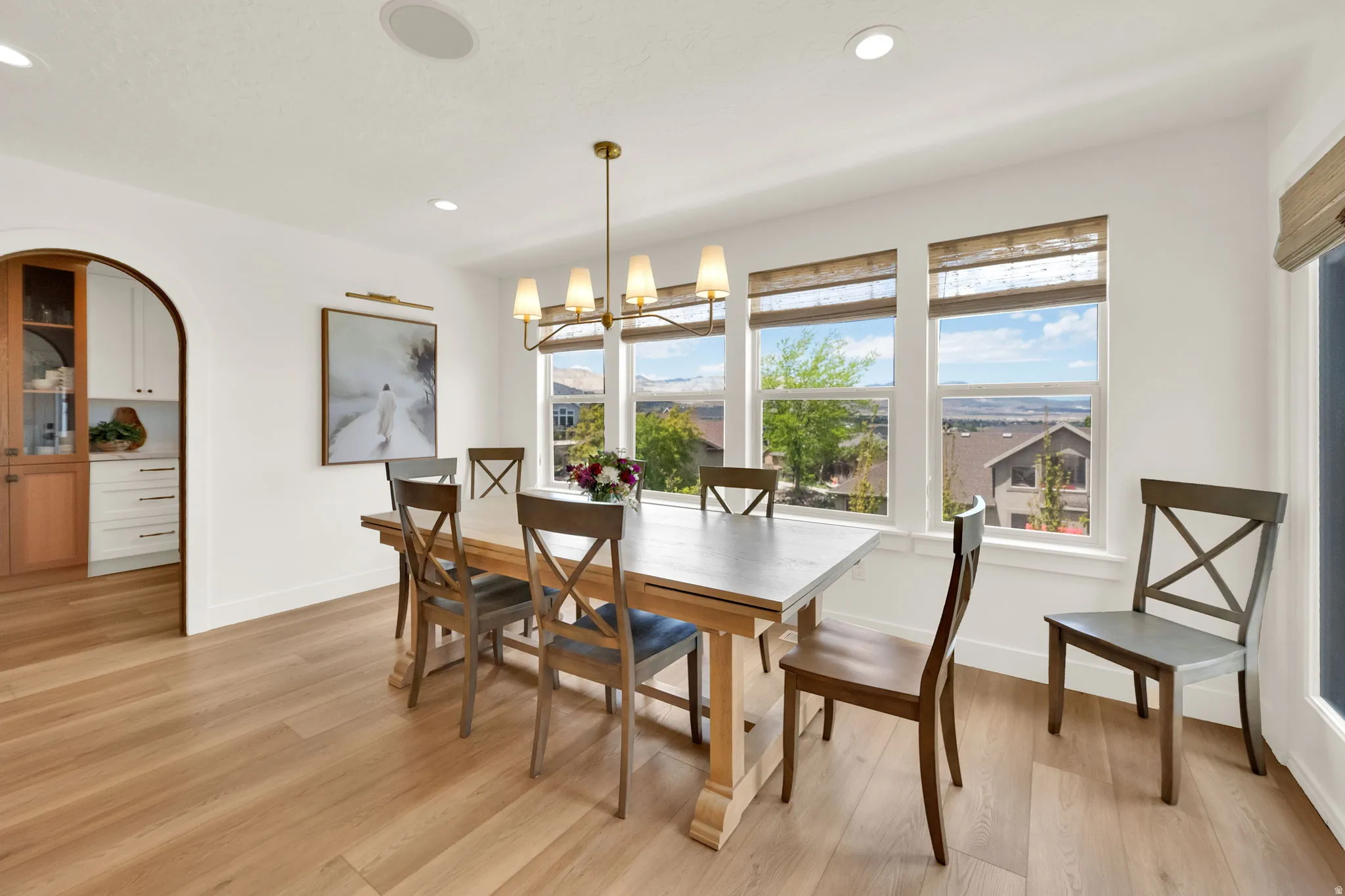 Spacious dining area featuring wood-finish flooring, a contemporary chandelier, recessed lighting, and an arched doorway