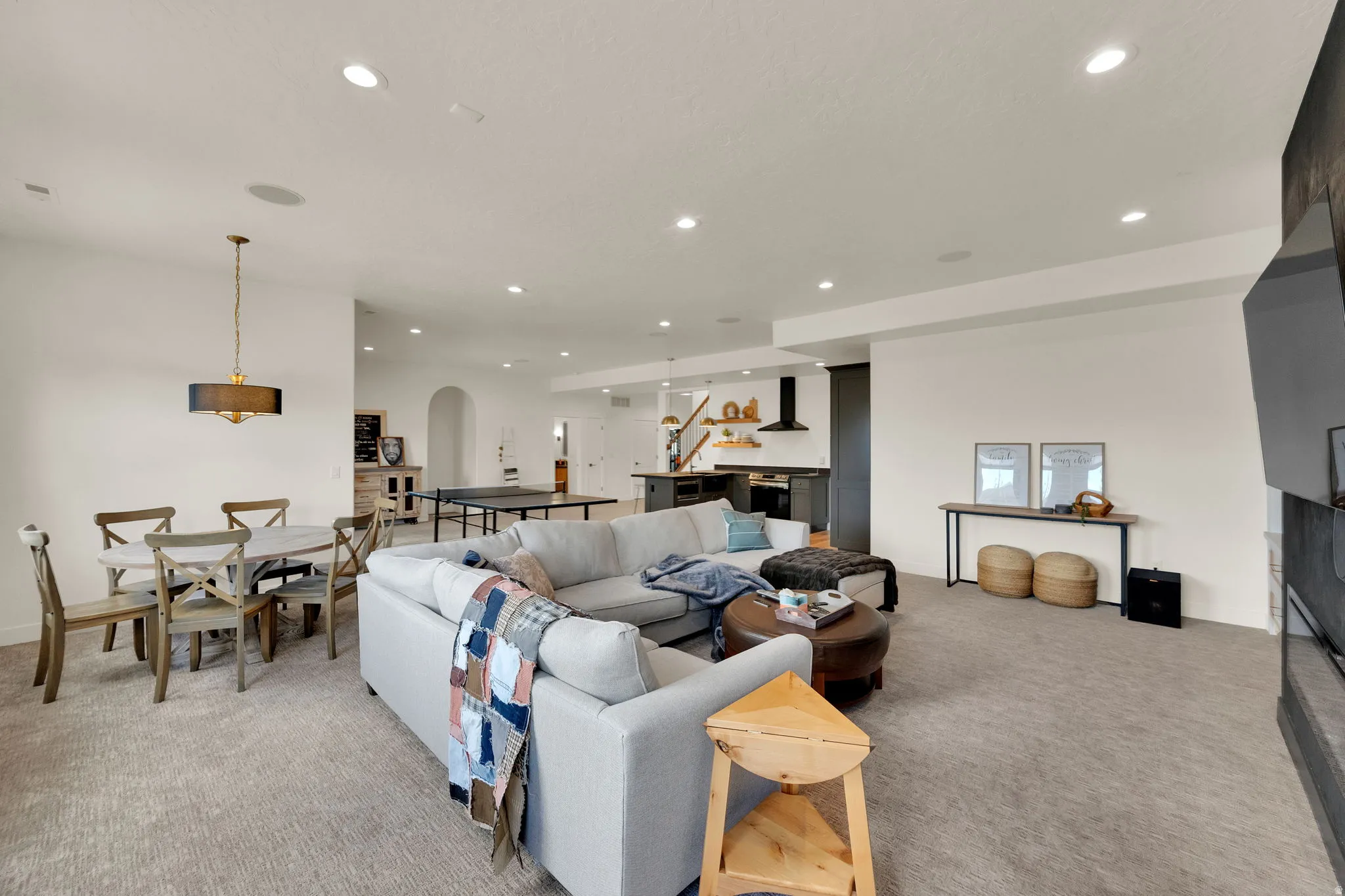 Spacious open-concept living area featuring recessed lighting, a modern chandelier, and a built-in kitchen hood