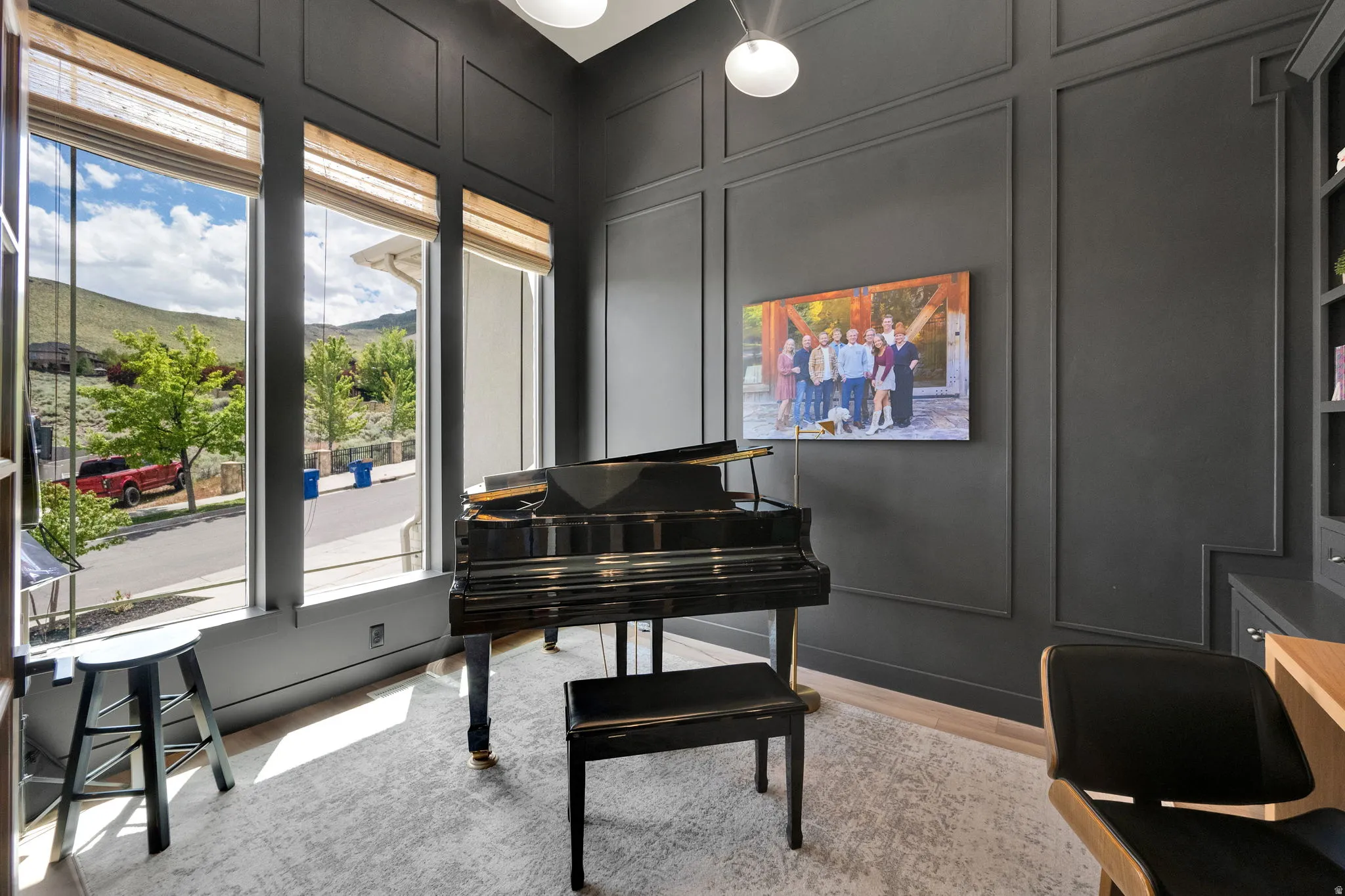 Interior space featuring multiple tall windows with natural light, dark paneled accent walls, built-in cabinetry, and wood-finish flooring
