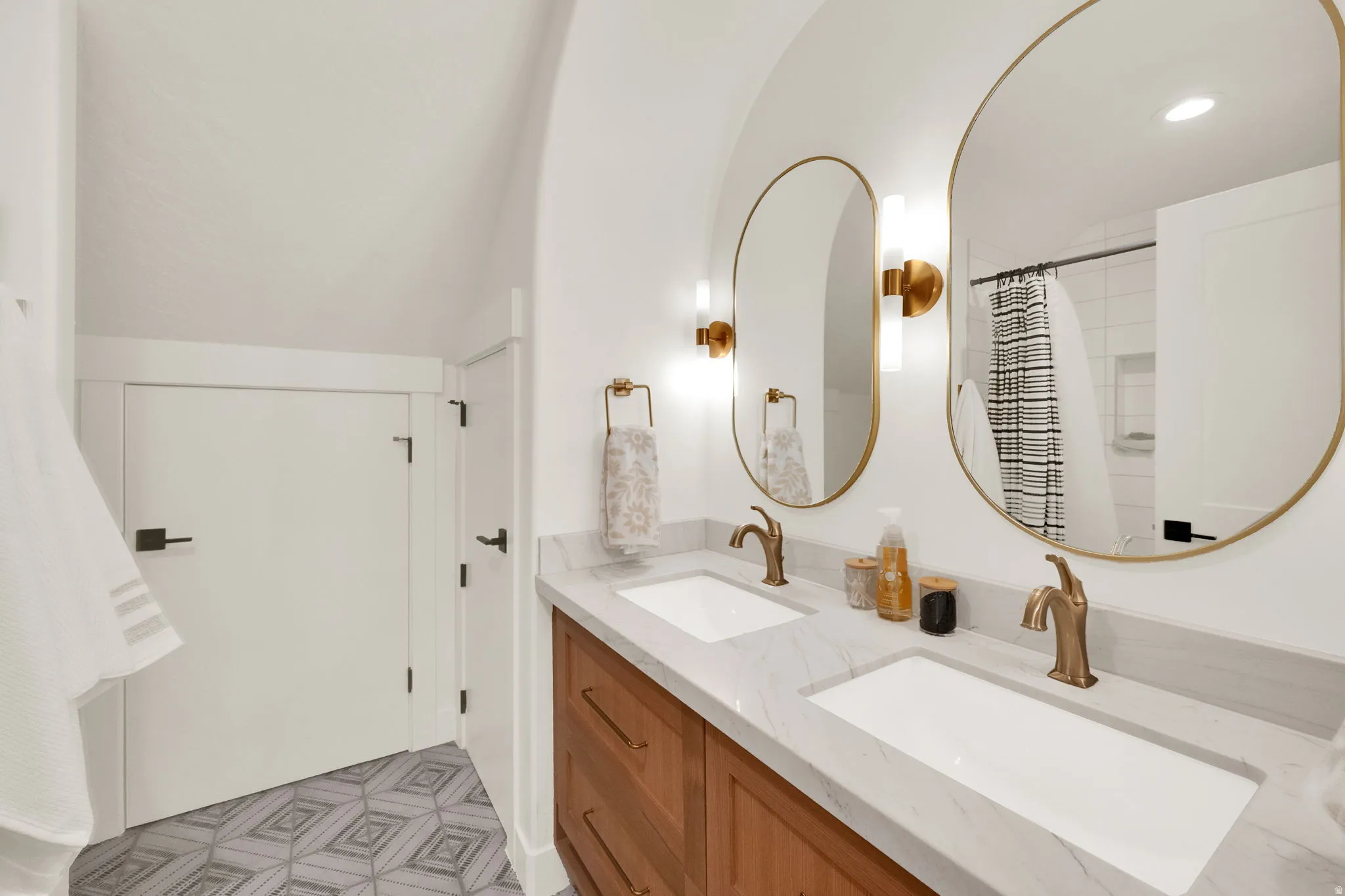 Double vanity featuring wood-finish cabinetry, white integrated sinks, and polished countertops