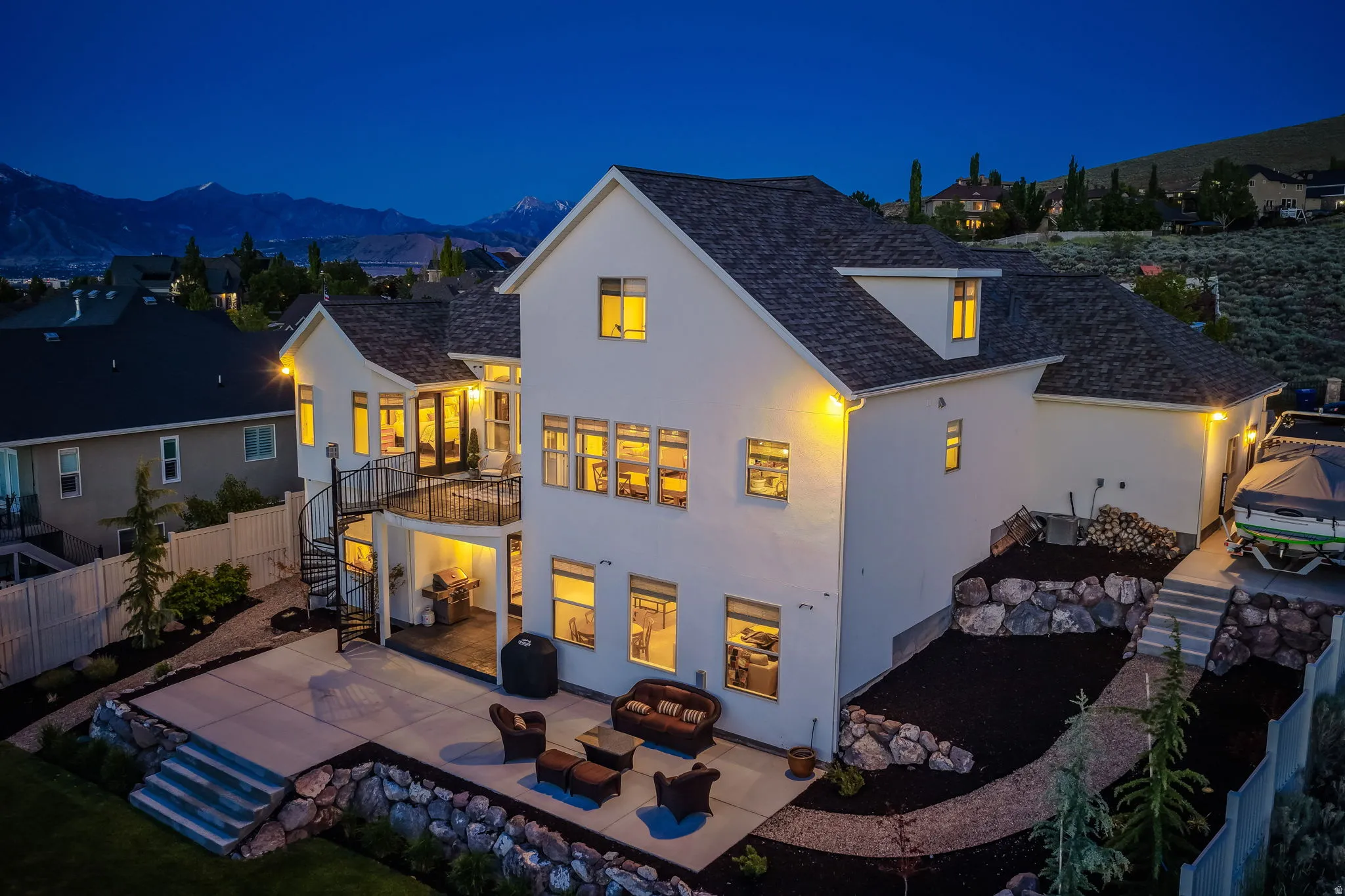 Rear exterior featuring a multi-level deck and patio, spiral staircase, and terraced landscaping