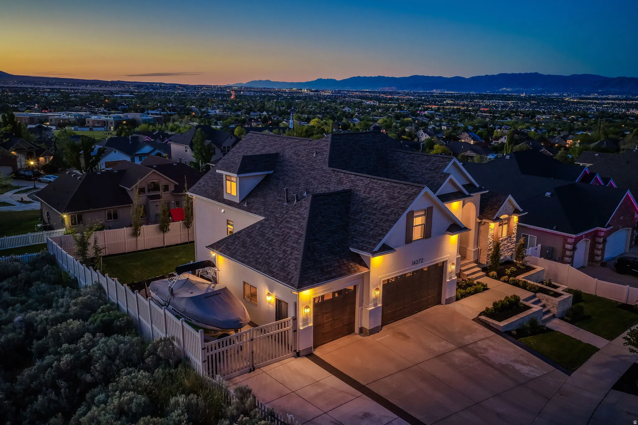 Contemporary two-story residence featuring a stone and stucco facade, a dark shingle roof, and exterior accent lighting