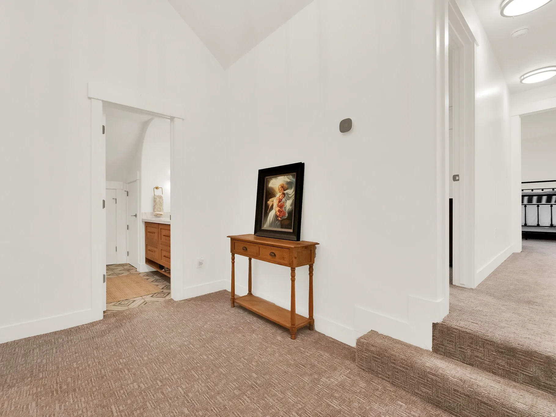 Hallway featuring vaulted ceilings, plush carpeted flooring, and white trim