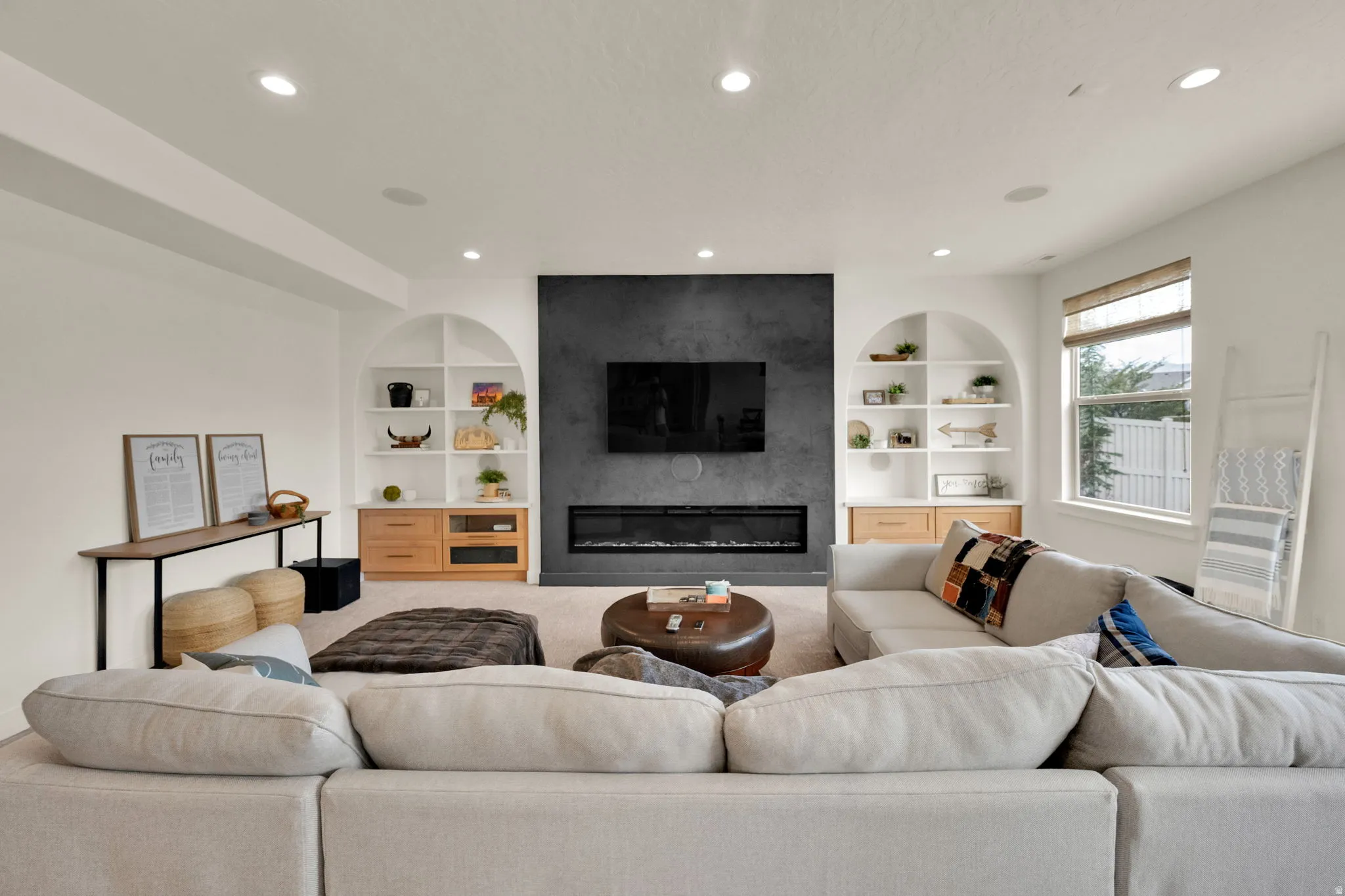 Living area featuring a modern fireplace with a dark accent wall, recessed lighting, and a window with natural light