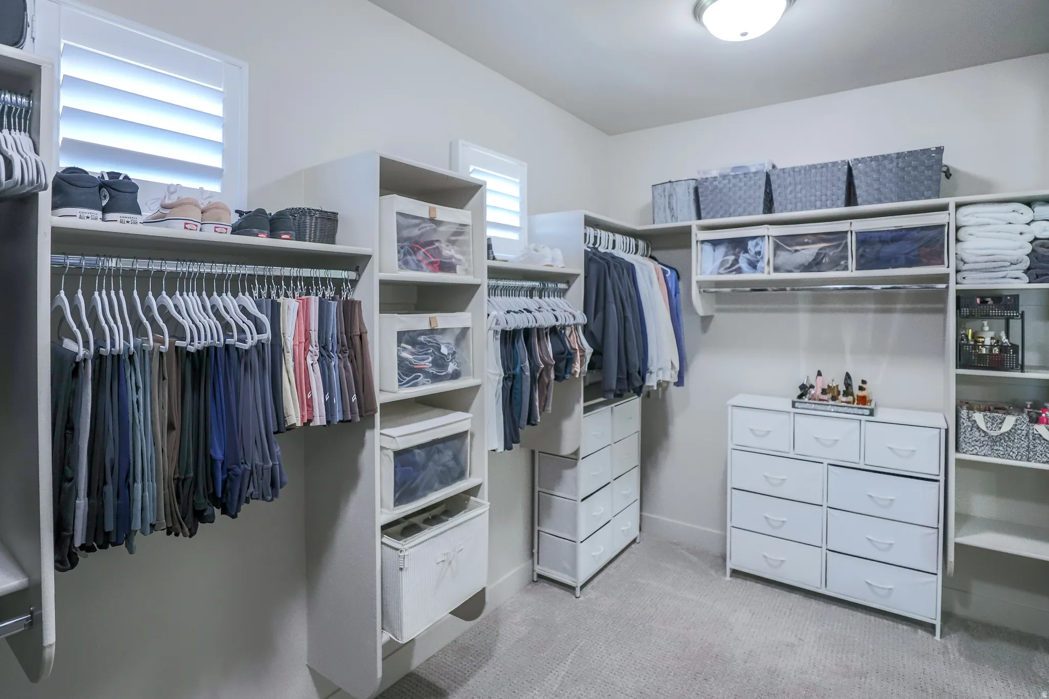 Custom closet system featuring multiple hanging rods, integrated shelving units, and drawer storage