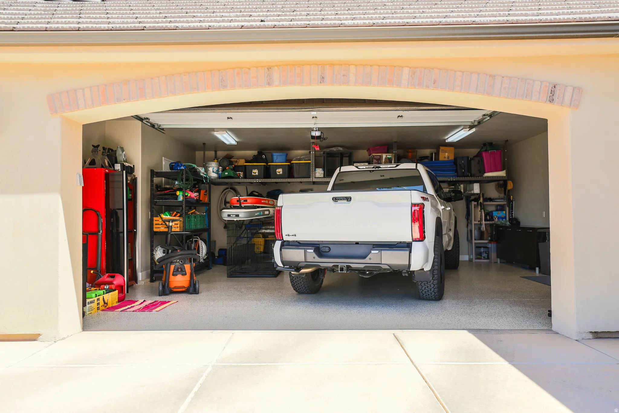 Garage with an epoxy-coated floor, overhead fluorescent lighting, and visible shelving