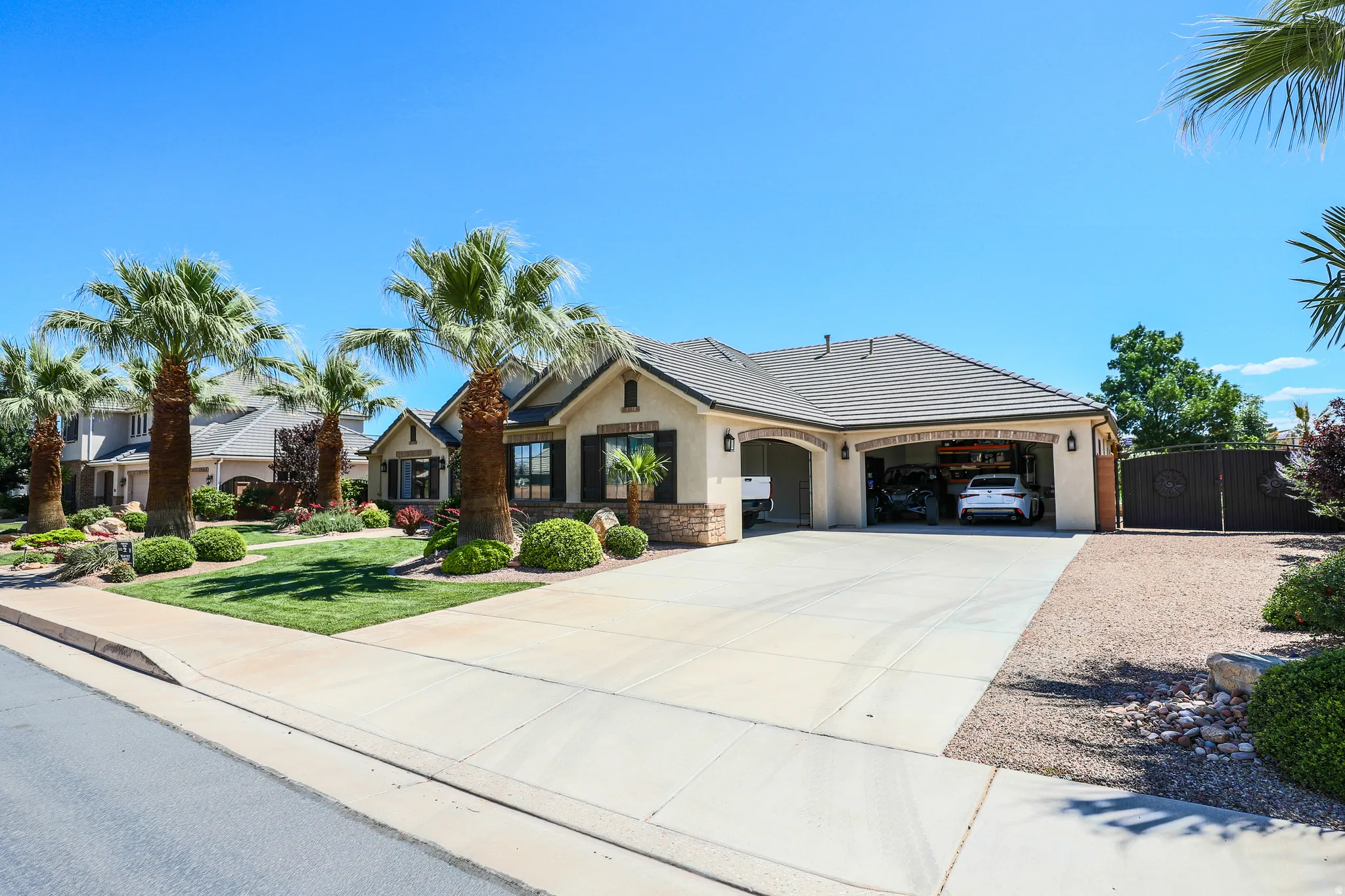 Stucco exterior with stone accents, a tile roof, and a multi-car garage
