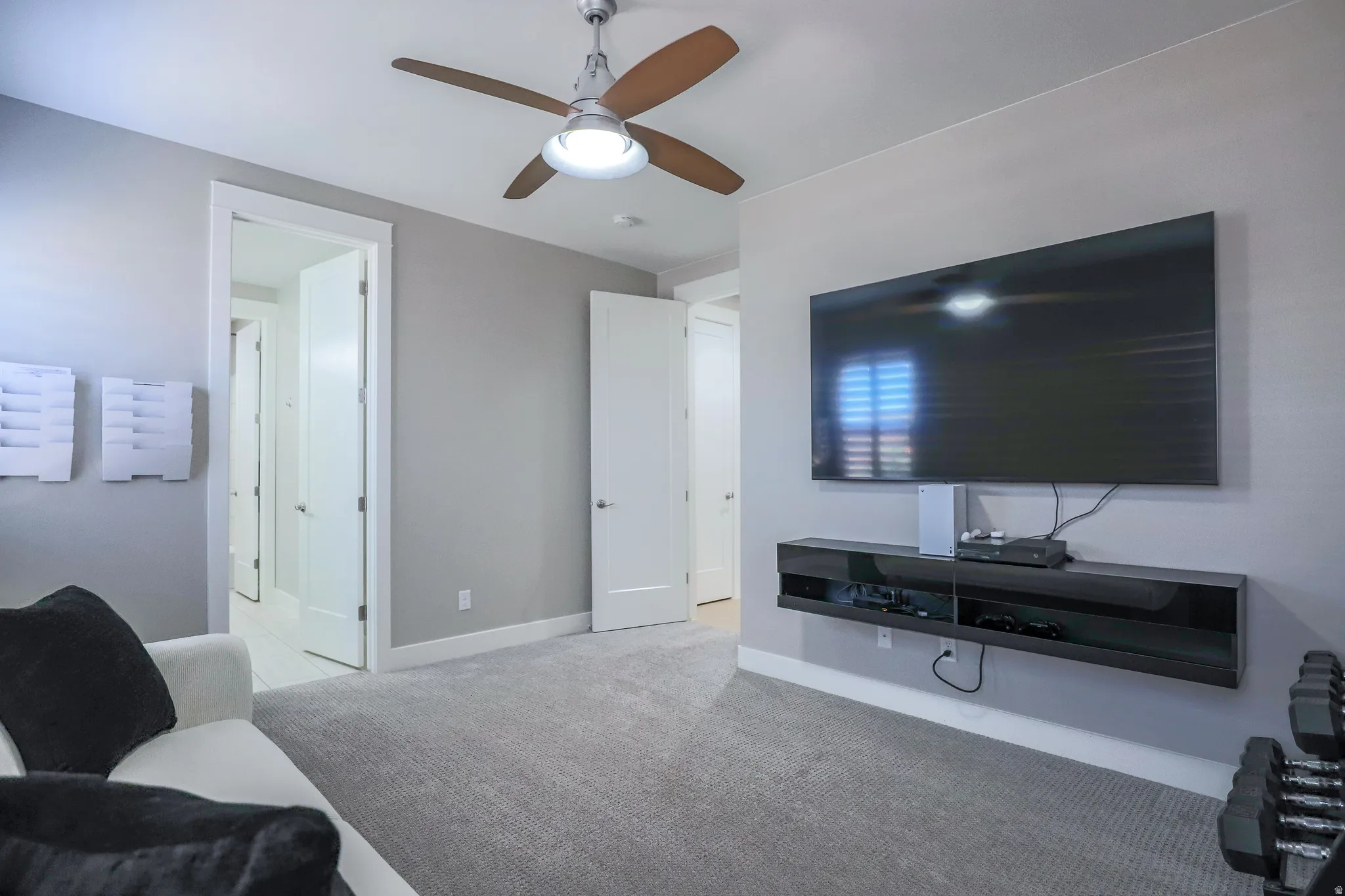 Spacious room with plush gray carpeting, recessed lighting, and a modern ceiling fan with wood-finish blades