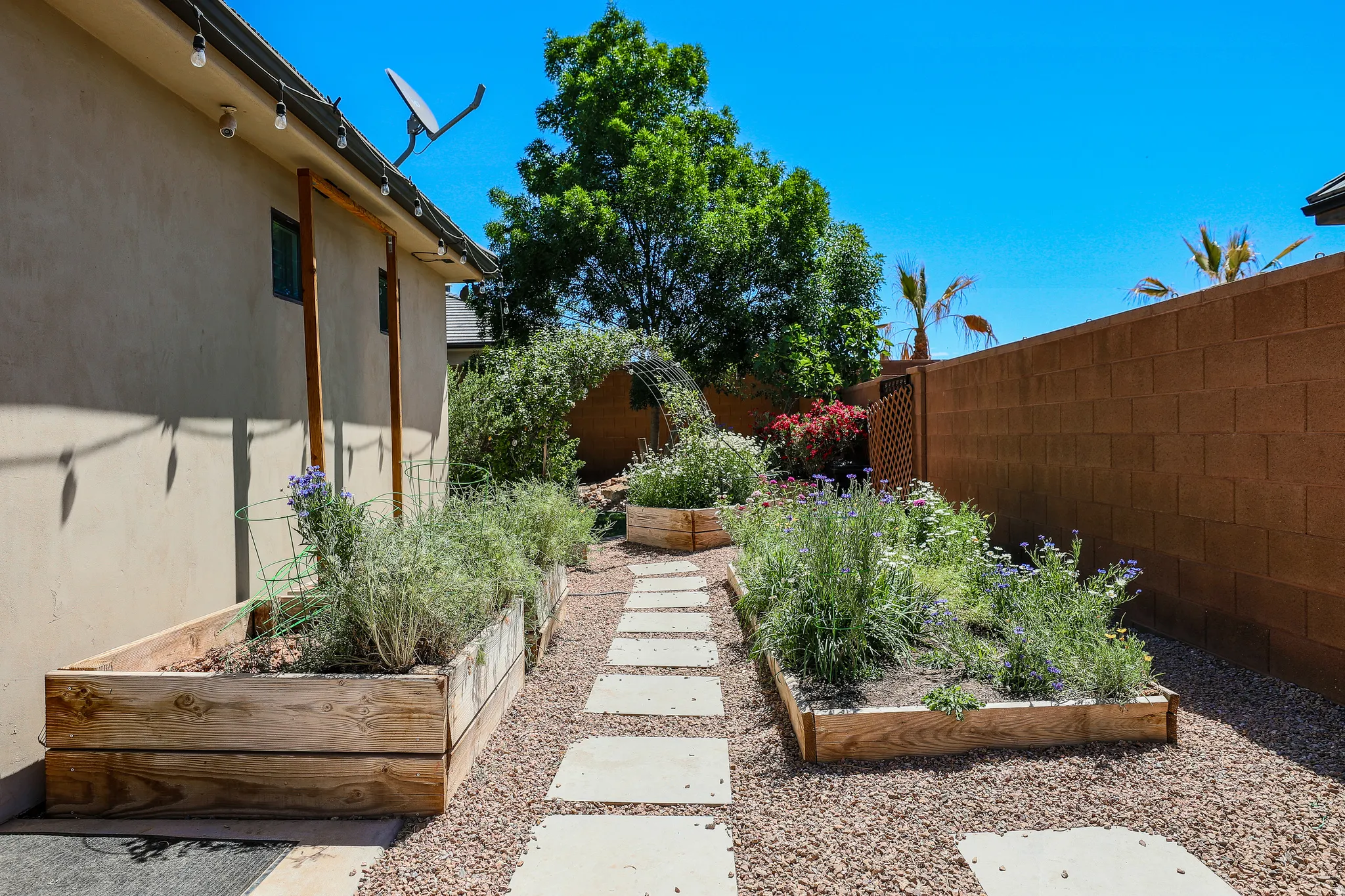 Backyard space featuring a paver pathway, gravel ground cover, and raised wooden planter boxes