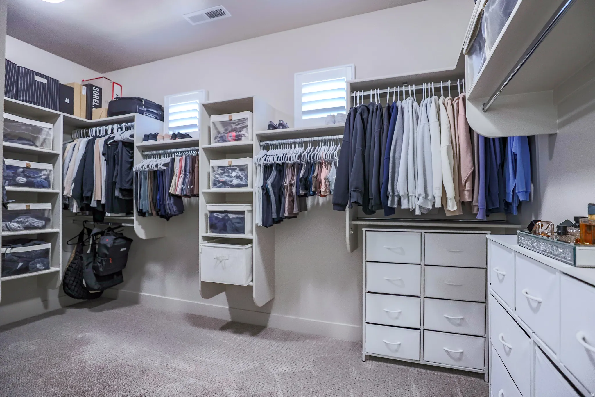 Custom closet system featuring multiple hanging rods, integrated shelving, and built-in drawers