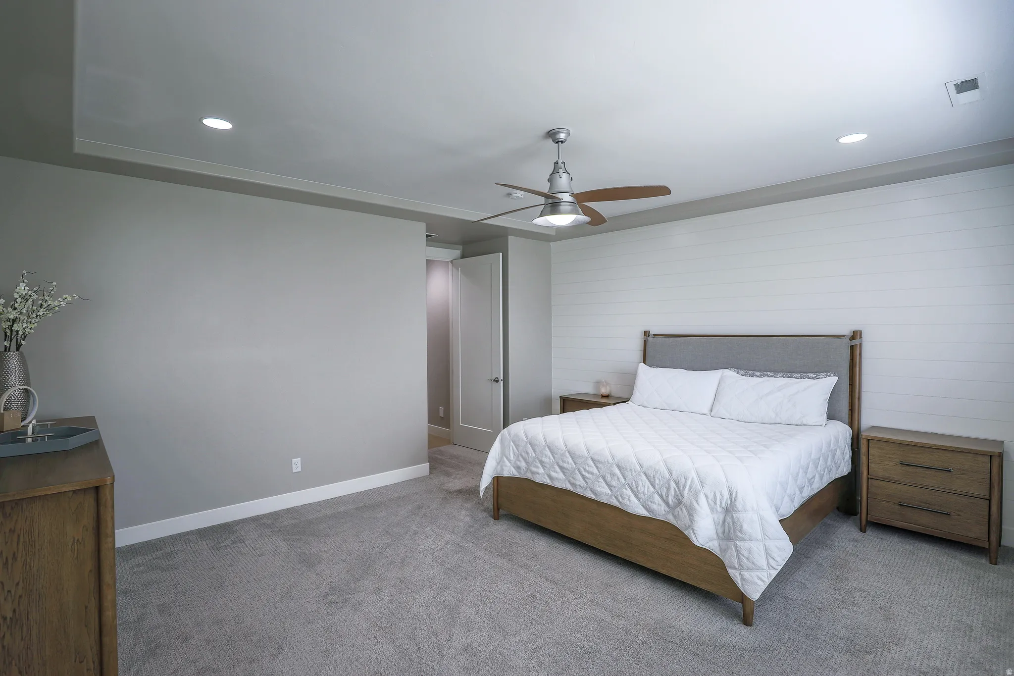 Recessed lighting illumination, tray ceiling accent, shiplap wall detail, and ceiling fan fixture