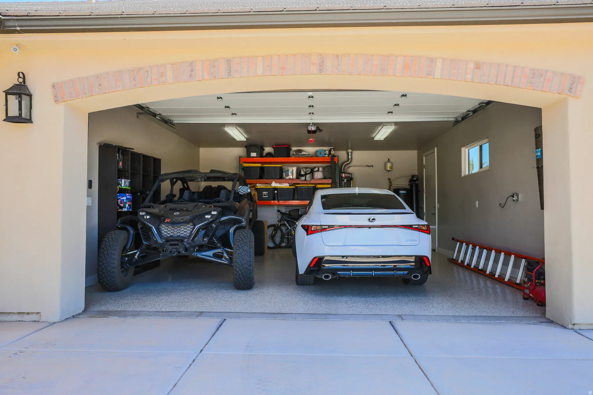 Spacious garage featuring a durable epoxy floor, overhead fluorescent lighting, a window for natural light, and built-in storage shelving