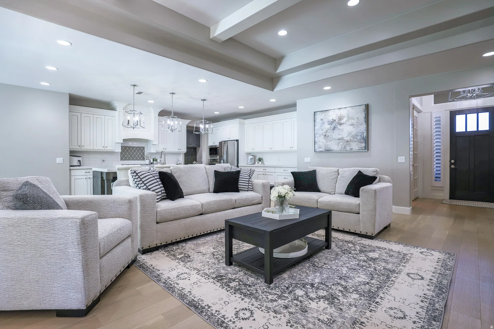 Open-concept living space featuring wood-finish flooring, recessed lighting, and a tray ceiling
