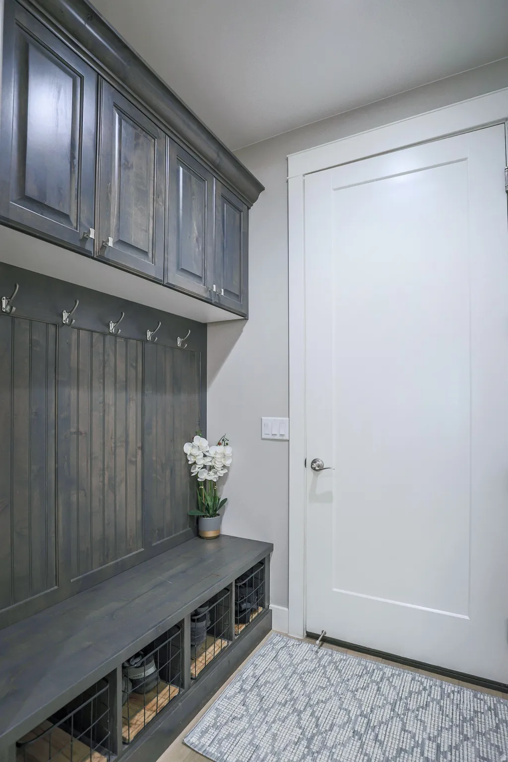 Built-in mudroom storage featuring dark wood-finish cabinetry, beadboard paneling, and a bench with integrated cubbies