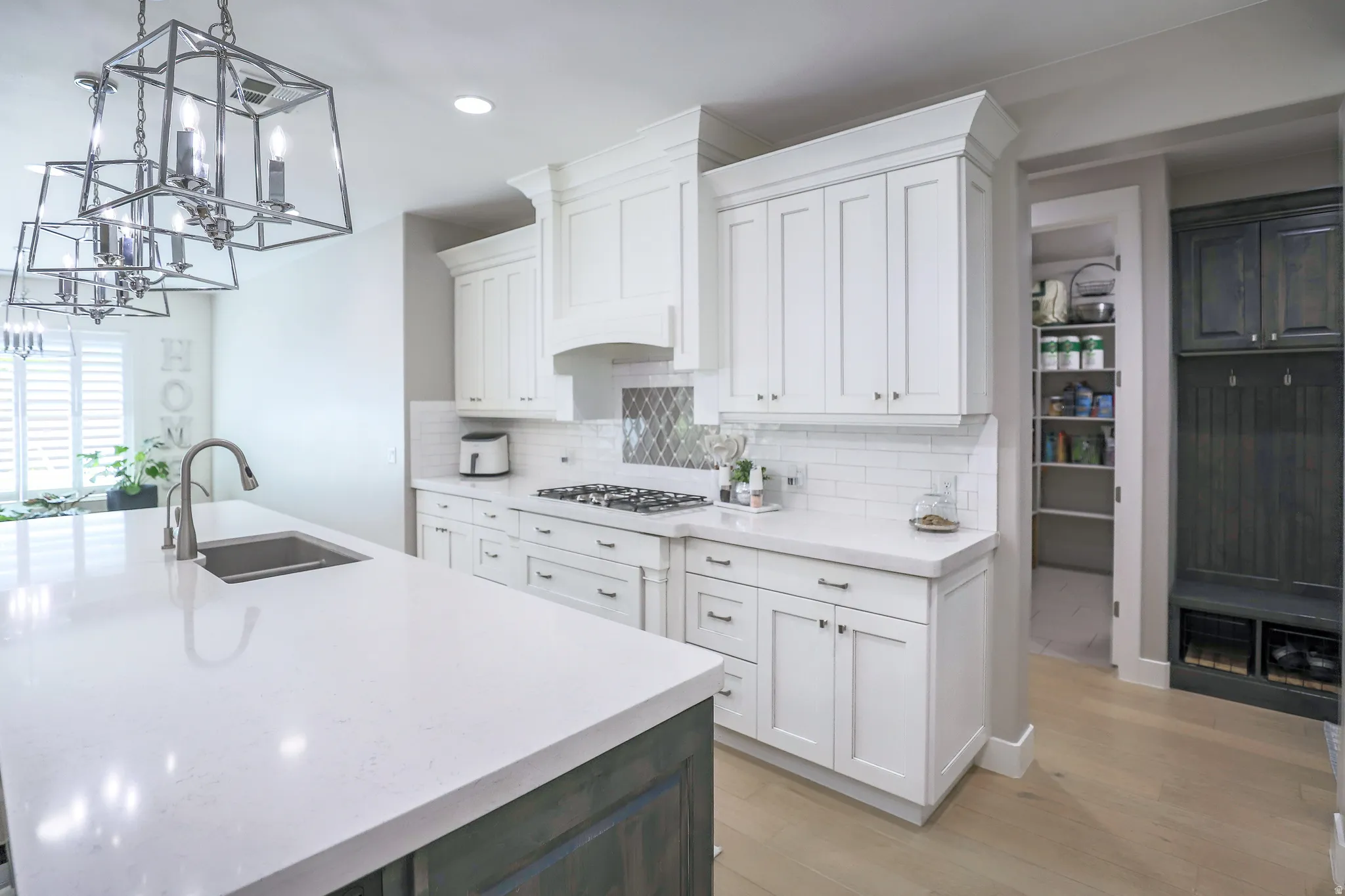 Open-concept kitchen featuring white shaker-style cabinetry, a built-in gas range, and a subway tile backsplash