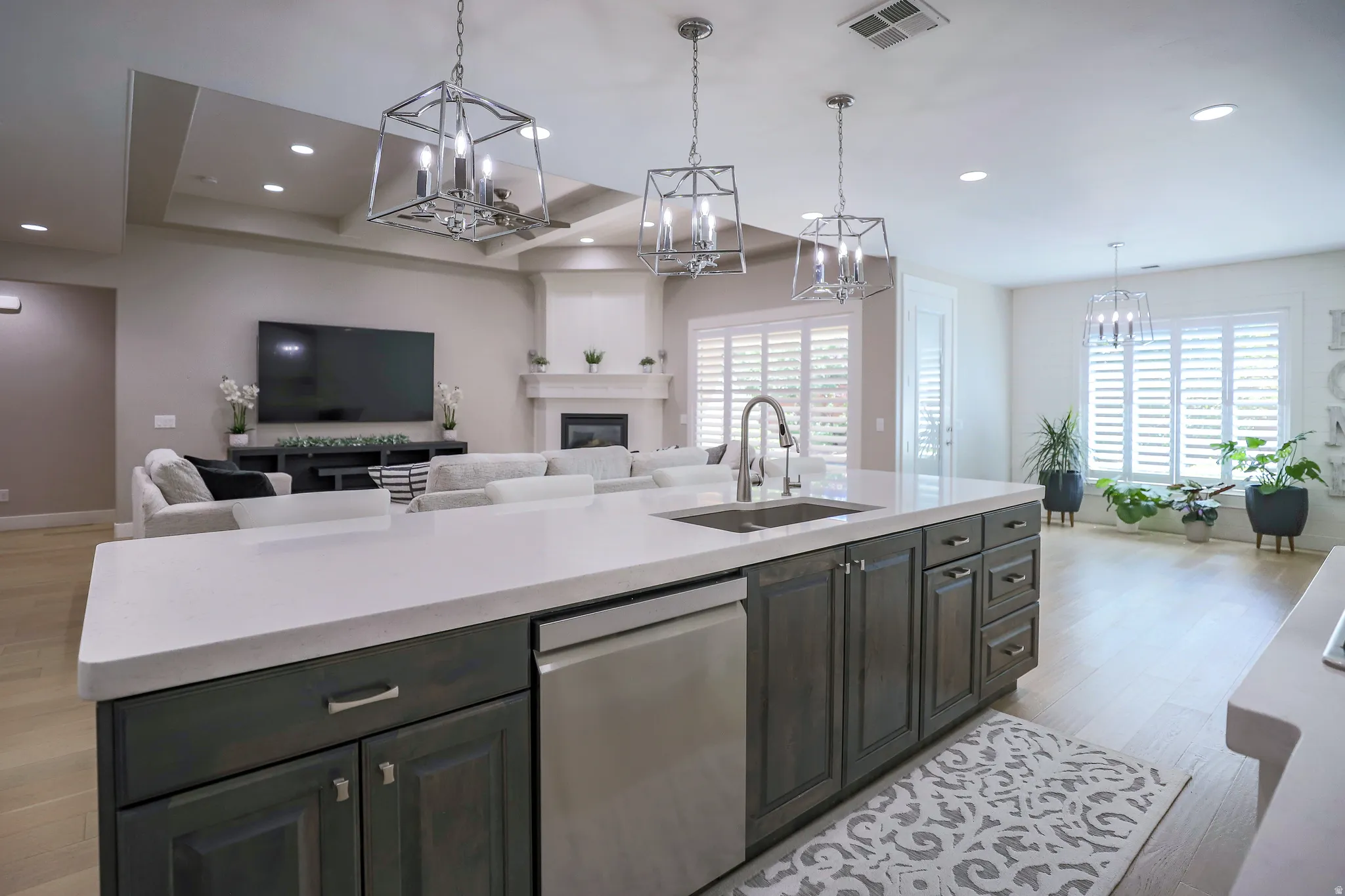 Kitchen island featuring a stainless steel sink with a gooseneck faucet, integrated dishwasher, and dark wood-finish cabinetry with silver hardware