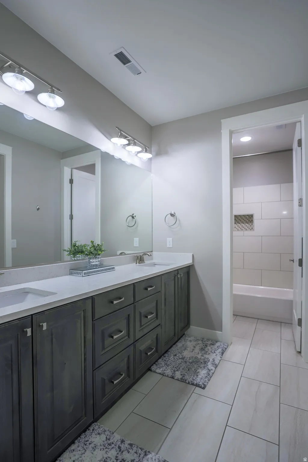 Bathroom featuring a dual vanity with dark wood-finish cabinetry, light-colored countertops, and two undermount sinks