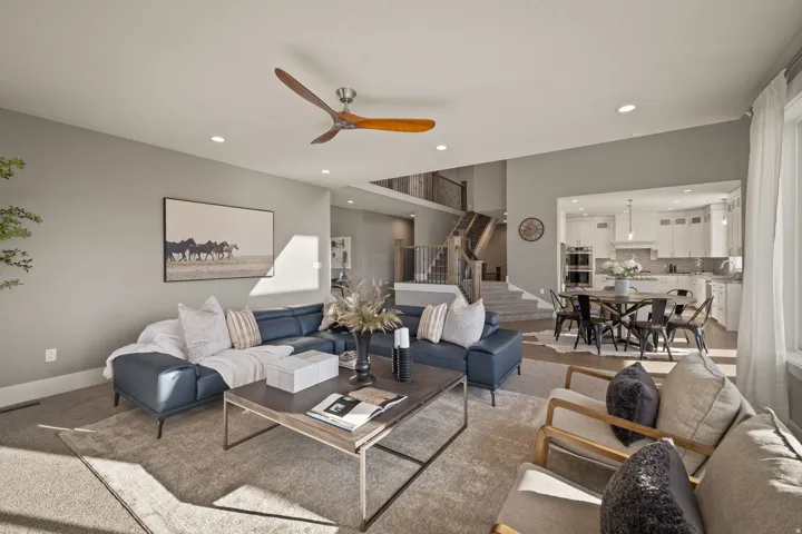 Spacious living area featuring neutral wall tones, recessed lighting, and a wood-finish ceiling fan