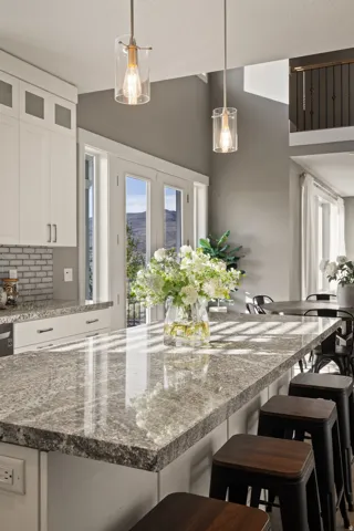 Kitchen island with a polished stone countertop, under-cabinet storage, and pendant lighting