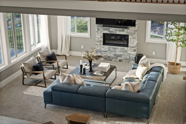 Living area featuring a floor-to-ceiling stone fireplace, large windows, and neutral carpeting