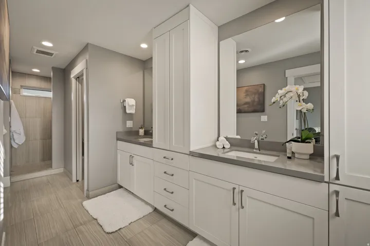 Dual vanity with white cabinetry and integrated sinks, complemented by a large mirror and recessed lighting